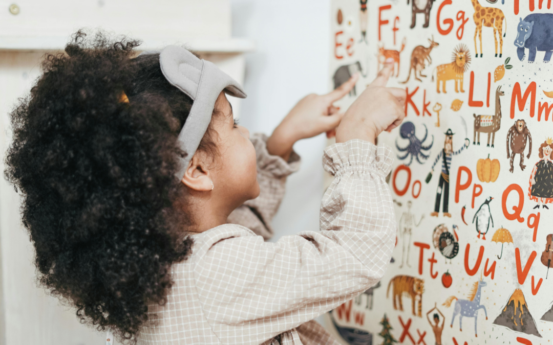 child pointing to whiteboard with alphabet