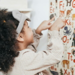 child pointing to whiteboard with alphabet