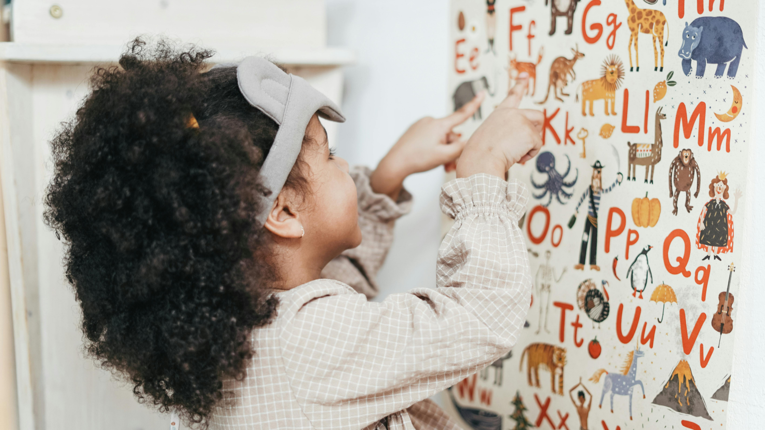 child pointing to whiteboard with alphabet